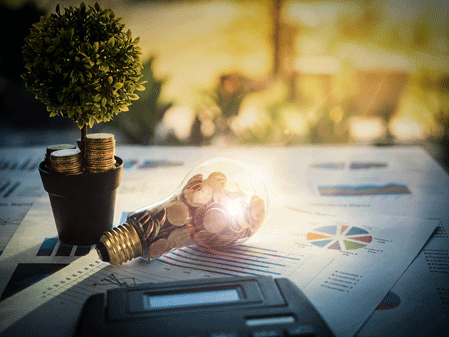 A light bulb with coin and tree, calculator on business graph.